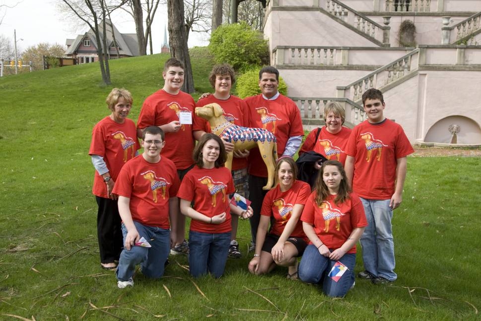 A group of teenagers in red shirts holding a plastic dog